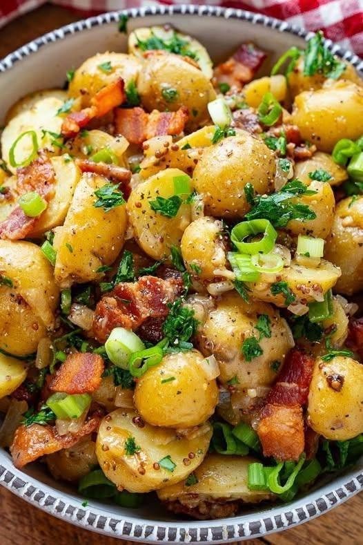 Loaded Garlic Butter Bacon Potato Salad Some potato salads are light and refreshing. And then there are potato salads that show up to the table and immediately become the main attraction. This Loaded Garlic Butter Bacon Potato Salad is definitely the second kind. It's creamy, buttery, garlicky, cheesy, and loaded with crispy bacon. The potatoes are tender on the inside, coated in rich garlic butter, and tossed with a creamy dressing before being finished with sharp cheddar and plenty of fresh green onions. I made this recently for a family meal, thinking it would simply be a side dish. It was not. People kept going back for another spoonful, and before long, there was hardly anything left in the bowl. That's when I knew this recipe needed to become a regular. I love potato salad because it feels like comfort food, but this version takes everything I love about a loaded baked potato and turns it into a ridiculously good salad. You've got the potatoes. You've got the bacon. You've got the cheese. You've got the creamy dressing. And then there's that garlic butter that gets into every little corner of the potatoes. Honestly, it's hard to stop at one serving. ❤️ Why You'll Love This Loaded Potato Salad Packed with crispy bacon Rich garlic butter flavor Creamy without being boring Loaded with sharp cheddar cheese Tender potatoes with plenty of flavor Easy to make ahead Perfect for cookouts and family dinners Delicious served warm, room temperature, or chilled Easy to customize Makes an impressive side dish without complicated cooking It's basically everything you love about a loaded baked potato in potato-salad form. And I'm completely okay with that. 🛒 Ingredients For the Potatoes 2½ pounds baby Yukon Gold or yellow potatoes 4 tablespoons unsalted butter 4 cloves garlic, finely minced 1 teaspoon salt, plus more for the cooking water ½ teaspoon freshly ground black pepper ½ teaspoon smoked paprika ½ teaspoon dried parsley For the Loaded Salad 8 ounces bacon 1 cup sharp cheddar cheese, shredded or cut into small cubes ½ cup sour cream ½ cup mayonnaise 1 tablespoon Dijon mustard 1 tablespoon lemon juice ½ teaspoon garlic powder ¼ teaspoon black pepper ½ cup sliced green onions 2 tablespoons chopped fresh parsley Optional Toppings Extra crispy bacon Extra cheddar Chopped chives Sliced jalapeños Sour cream Fresh parsley Cracked black pepper 🥔 Choosing the Best Potatoes For potato salad, I love using Yukon Gold or baby yellow potatoes. They have a naturally buttery texture and hold their shape well after cooking. Red potatoes are another excellent choice. I usually avoid very starchy potatoes if I'm making a traditional creamy potato salad because they can become too soft or break apart easily. The goal is tender potatoes that still hold their shape when you toss everything together. 👩🍳 How to Make Loaded Garlic Butter Bacon Potato Salad 1. Cook the Bacon Start with the bacon because you'll want plenty of crispy bacon pieces throughout the salad. Place the bacon in a large skillet over medium heat. Cook until deeply golden and crisp, turning as needed. Transfer the bacon to a paper-towel-lined plate. Let it cool, then crumble or chop it into bite-sized pieces. Reserve a little of the bacon for sprinkling over the finished salad. Don't throw away all that bacon flavor left in the skillet just yet. 🥔 2. Cook the Potatoes Wash the potatoes thoroughly. If they're small, you can leave them whole. If they're larger, cut them into bite-sized pieces. Place the potatoes in a large pot and cover them with cold water. Add a generous pinch of salt. Bring the water to a boil, then reduce to a gentle simmer. Cook for approximately 10–15 minutes, or until the potatoes are fork-tender. You want them cooked through but not falling apart. Potato salads work best when the potatoes retain enough structure to hold their shape after dressing. 🧄 3. Make the Garlic Butter While the potatoes are cooking, melt the butter in a small saucepan or skillet over low heat. Add the minced garlic. Cook for about 30–60 seconds, stirring frequently. You want the garlic fragrant and lightly softened. Don't let it become dark brown or burnt. Add the smoked paprika, dried parsley, black pepper, and a small pinch of salt. Stir everything together. The smell at this point is going to be incredible. 🧈 4. Drain and Coat the Potatoes Once the potatoes are tender, drain them thoroughly. Let them sit in the colander for a minute or two so excess moisture can evaporate. Transfer the warm potatoes to a large mixing bowl. Pour the warm garlic butter over them. Gently toss until every potato is coated. This is one of my favorite steps because the warm potatoes absorb the garlic butter beautifully. Adding flavorful dressing while potatoes are still warm is a common technique for helping them absorb more flavor. 🥓 5. Make the Creamy Dressing In a separate bowl, whisk together: Sour cream Mayonnaise Dijon mustard Lemon juice Garlic powder Black pepper Taste the dressing. If you like a little more tang, add another splash of lemon juice. If you want it creamier, add another spoonful of sour cream. 🧀 6. Add the Good Stuff Add the crispy bacon to the warm garlic-butter-coated potatoes. Add the cheddar cheese. Add the sliced green onions and chopped parsley. Pour the creamy dressing over everything. 🥄 7. Toss Gently Use a large spoon or rubber spatula to gently toss everything together. Don't stir aggressively. You want the potatoes to remain chunky rather than turning into mashed potatoes. If a few potatoes break apart, that's completely fine. Those little creamy potato pieces actually make the salad even better. ❄️ 8. Chill or Serve Warm You have two options here. Serve It Warm If you like a warm, extra-cozy potato salad, serve it shortly after mixing. The cheese will soften slightly, the garlic butter will still be fragrant, and the bacon will have plenty of texture. Serve It Chilled Cover and refrigerate for about 30–60 minutes. The flavors will meld together beautifully as the salad chills. I actually love it both ways. 🥓 9. Finish With Toppings Just before serving, sprinkle the reserved bacon over the top. Add another handful of shredded cheddar. Finish with green onions, parsley, or chives. If you're making this for a gathering, don't be shy with the toppings. A few extra crispy bacon pieces on top make the whole bowl look irresistible. ⭐ Tips for the Best Potato Salad Don't overcook the potatoes Soft potatoes are good. Mushy potatoes are not. Start checking them early and remove them as soon as a fork slides through easily. Salt the cooking water Potatoes absorb flavor while they cook, so seasoning the water makes a noticeable difference. Let the potatoes drain well Excess water can dilute the creamy dressing. Dress them while warm The warm potatoes absorb the garlic butter beautifully. Don't overdress Start with most of the dressing and add more if needed. You can always add more. Use freshly cooked bacon Crispy bacon gives you the best texture. Don't skimp on garlic This is garlic butter bacon potato salad, after all. 🧄 Make the Garlic Flavor Even Bigger If you're a serious garlic lover, there are several ways to intensify the flavor. Fresh Garlic Use an extra clove or two in the garlic butter. Garlic Powder Add another ¼ teaspoon to the creamy dressing. Roasted Garlic Mash a few roasted garlic cloves into the dressing for a sweeter, deeper garlic flavor. Garlic Butter Bacon Drizzle Reserve a tablespoon of the garlic butter and drizzle it over the finished salad. 🧀 Best Cheese Choices Sharp cheddar is my first choice because it gives the salad a strong cheesy flavor. But you can easily switch things up. Monterey Jack Milder and extra creamy. Colby Jack Great melting quality and a mild flavor. Pepper Jack Perfect if you like some heat. Smoked Cheddar Adds a wonderful smoky flavor. Parmesan A little Parmesan mixed into the garlic butter adds savory depth. You can also use a combination. Sharp cheddar plus Monterey Jack is especially good. 🌶️ Easy Variations Jalapeño Bacon Potato Salad Add finely diced fresh jalapeños. For extra heat, use pepper Jack cheese. Ranch Loaded Potato Salad Add a little ranch seasoning to the creamy dressing. BBQ Bacon Potato Salad Drizzle a little sugar-free or regular BBQ sauce over the finished salad, depending on your preference. Green Onion & Cheddar Potato Salad Skip some of the other toppings and really let the cheddar and green onions shine. Loaded Breakfast Potato Salad Add chopped hard-boiled eggs and extra bacon. Smoky Garlic Potato Salad Use smoked cheddar and a little extra smoked paprika. Extra Cheesy Potato Salad Fold in another ½ cup of cheese and sprinkle more on top. Because there is really no such thing as too much cheese here. 🍳 Add Hard-Boiled Eggs If you want an even more substantial loaded potato salad, add 4 hard-boiled eggs, chopped. Eggs pair beautifully with bacon, potatoes, cheddar, and creamy dressing. They also make the salad feel especially classic. 🥗 What to Serve With Loaded Garlic Butter Bacon Potato Salad This is a hearty side dish, so it works beautifully with simple mains. Serve it alongside: Grilled chicken BBQ chicken Burgers Steak Grilled sausages Pulled pork BBQ ribs Grilled shrimp Roast chicken Grilled vegetables It's especially good at a backyard barbecue. Put out a big bowl alongside grilled meat, corn, salad, and fresh fruit, and you've got an easy summer spread. 🥪 Make It Lunch You don't have to wait for a cookout. A scoop of this potato salad makes a great lunch alongside: Grilled chicken Turkey Ham Boiled eggs Green salad Cucumber slices You can even serve it with leftover grilled meat for an easy next-day meal. 🧊 Can You Make This Potato Salad Ahead? Absolutely. In fact, this is one of those recipes that benefits from a little time in the refrigerator. Make it several hours before serving and refrigerate it covered. The potatoes have time to absorb the garlic, butter, bacon, and dressing flavors. If the salad seems slightly dry after chilling, stir in a tablespoon or two of sour cream or mayonnaise before serving. 🧊 How to Store Leftovers Transfer leftover potato salad to an airtight container and refrigerate promptly. For best quality, use it within 3–4 days. Keep it refrigerated until you're ready to serve it. Creamy potato salads containing mayonnaise and dairy are perishable, so avoid leaving them at room temperature for extended periods. ❄️ Can You Freeze Potato Salad? I don't recommend freezing this particular salad. The potatoes can become watery or grainy after thawing, while the creamy dressing may separate. It's much better to make it fresh and refrigerate the leftovers. 🥓 How to Keep the Bacon Crispy This is a big one. If you mix all the bacon into the salad several hours before serving, some of it will soften. For the best texture: Mix most of the bacon into the salad. Reserve some bacon for topping. Add the reserved crispy bacon immediately before serving. That way you get both flavors and texture. ❓ Frequently Asked Questions Can I use red potatoes? Absolutely. Red potatoes work very well because they hold their shape nicely after cooking. Can I use russet potatoes? Yes, although russets are starchier and softer. Be especially careful not to overcook them. Can I make this potato salad without mayonnaise? Yes. Use additional sour cream or Greek yogurt instead. The flavor will be slightly tangier and lighter. Can I use Greek yogurt? Definitely. Plain full-fat Greek yogurt makes a good substitute for some or all of the sour cream. Can I make it without bacon? Yes. You'll lose the smoky, salty bacon flavor, but the garlic butter and cheese still make a delicious potato salad. Can I use turkey bacon? Yes. Turkey bacon can work if that's your preference, although the flavor and richness will be different. Can I make this vegetarian? Yes. Leave out the bacon and use vegetarian-friendly cheese. You can add smoked paprika or smoked cheese for extra depth. Can I serve it warm? Absolutely. It's delicious warm, at room temperature, or chilled. Why did my potatoes fall apart? They were probably overcooked. Start testing the potatoes before the minimum cooking time is reached and drain them as soon as they're fork-tender. Why is my potato salad watery? The potatoes may not have drained thoroughly, or the dressing may have been too thin. Let the potatoes steam-dry briefly after draining and add dressing gradually. How do I make it more garlicky? Add more fresh garlic to the butter or a little extra garlic powder to the dressing. For a sweeter garlic flavor, try roasted garlic. Can I add ranch seasoning? Yes. Ranch seasoning is an easy way to give this already-loaded potato salad another layer of flavor. Can I make it spicy? Absolutely. Add jalapeños, cayenne, hot sauce, or pepper Jack cheese. How long should potato salad chill? About 30–60 minutes is enough to bring the flavors together, although it can be made several hours ahead. 📝 Recipe at a Glance Recipe: Loaded Garlic Butter Bacon Potato Salad Prep Time: 15 minutes Cook Time: 20 minutes Chill Time: 30–60 minutes, optional Total Time: About 35–95 minutes Servings: 6–8 Category: Side Dish / Salad Cuisine: American-inspired Method: Stovetop Ingredients Potatoes 2½ pounds baby Yukon Gold potatoes 4 tablespoons unsalted butter 4 cloves garlic, minced 1 teaspoon salt ½ teaspoon black pepper ½ teaspoon smoked paprika ½ teaspoon dried parsley Loaded Filling 8 ounces bacon 1 cup sharp cheddar ½ cup sour cream ½ cup mayonnaise 1 tablespoon Dijon mustard 1 tablespoon lemon juice ½ teaspoon garlic powder ½ teaspoon black pepper ½ cup green onions 2 tablespoons fresh parsley Instructions Cook bacon until crisp; drain and crumble. Wash and cut potatoes into bite-sized pieces. Boil potatoes in salted water until fork-tender, about 10–15 minutes. Melt butter over low heat. Add garlic, smoked paprika, parsley, salt, and pepper; cook briefly until fragrant. Drain potatoes thoroughly. Toss warm potatoes with garlic butter. Whisk together sour cream, mayonnaise, Dijon, lemon juice, garlic powder, and pepper. Add bacon, cheddar, green onions, and parsley to the potatoes. Gently fold in the creamy dressing. Serve warm or chill for 30–60 minutes. Finish with extra bacon, cheddar, and green onions. ❤️ The Potato Salad That Steals the Show There are recipes you make because you need something to put next to the main dish. And then there are recipes that make everyone forget about the main dish. This Loaded Garlic Butter Bacon Potato Salad has a little bit of that magic. It's creamy without being bland. It's rich without needing complicated ingredients. The garlic butter gives the potatoes so much flavor, the crispy bacon adds that salty crunch, and the cheddar brings everything together. Then you get the fresh green onions cutting through all that richness. It's comforting. It's hearty. It's ridiculously satisfying. I love making a big bowl for family dinners, summer cookouts, holidays, or lazy weekends when everyone is grazing around the kitchen. And if you're anything like me, you'll probably find yourself sneaking a forkful straight from the refrigerator the next day. Because somehow potato salad tastes even better when you think you're just taking "one little bite." And then suddenly you're standing there eating another forkful. That's when you know you've made a good one.
