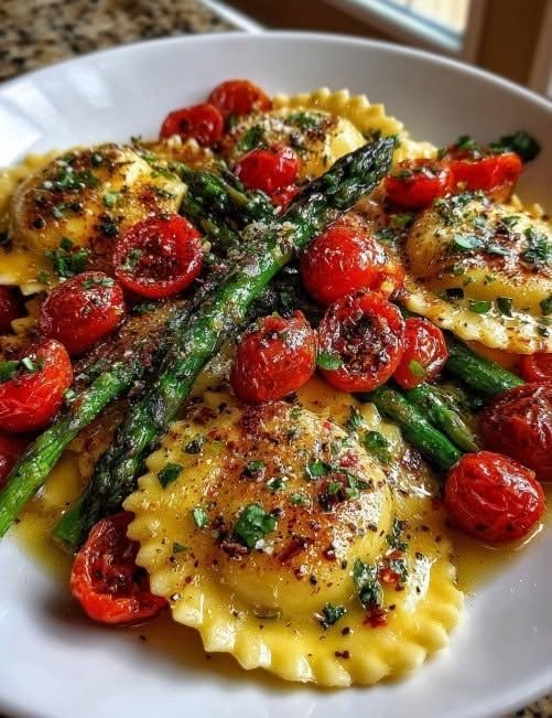 Ravioli with Cherry Tomatoes, Asparagus, Garlic, and Herbs There are some pasta dinners that feel like they belong on a restaurant menu, even though they take barely any effort to make at home. This Ravioli with Cherry Tomatoes, Asparagus, Garlic, and Herbs is exactly that kind of meal. I love it for those evenings when I want something comforting but don't want a heavy cream sauce or a complicated recipe. A package of cheese ravioli makes the whole thing wonderfully easy, while fresh asparagus and juicy cherry tomatoes make dinner feel bright, colorful, and fresh. The first time I made this combination, I was looking for a way to make a simple package of ravioli feel a little more special. I had asparagus in the refrigerator, a handful of cherry tomatoes on the counter, and some fresh herbs that needed using. So I tossed everything into a skillet with plenty of garlic and olive oil. A little lemon at the end made all the difference. The finished dish was so much better than I expected. The tomatoes became soft and juicy, the asparagus stayed slightly crisp, and the ravioli picked up all those garlicky, herby flavors. It became one of those recipes I reach for when I want dinner to feel homemade without spending the whole evening cooking. And honestly, that's my favorite kind of recipe. ❤️ Why You'll Love This Ravioli Recipe It's ready in about 25 minutes The ravioli cooks quickly, and the vegetables only need a few minutes in the skillet. Similar versions of this dish come together in about 25 minutes. It's colorful and fresh Bright green asparagus and red cherry tomatoes make this pasta look beautiful before you've even added the herbs and Parmesan. No heavy cream sauce The sauce is made with olive oil, garlic, a little pasta water, lemon juice, and Parmesan. It's light enough for a weeknight but still flavorful and satisfying. It's incredibly versatile Use cheese ravioli, mushroom ravioli, spinach ravioli, or even a meat-filled variety. It's perfect for spring and summer Fresh asparagus, tomatoes, basil, and parsley give this pasta a wonderfully fresh feel. 🛒 Ingredients You'll Need Cheese Ravioli I usually use refrigerated cheese ravioli because it cooks quickly and has a lovely tender texture. You'll need about 20 ounces. Frozen ravioli works too—just follow the package cooking instructions. Asparagus Choose firm, bright-green asparagus. Trim off the woody ends and cut the stalks into roughly 2-inch pieces. I like the asparagus to remain slightly crisp rather than becoming completely soft. Cherry Tomatoes Cherry or grape tomatoes both work beautifully. Halve them before adding them to the skillet so they soften more quickly and release some of their juices. Garlic Use fresh garlic if possible. Three or four cloves give the dish plenty of flavor without overwhelming the vegetables. Olive Oil Extra-virgin olive oil forms the base of the light sauce. Fresh Herbs Fresh basil and parsley make a big difference here. The basil adds sweetness while parsley brings a clean, fresh flavor. Lemon A little fresh lemon juice brightens the entire dish. Don't skip it if you can help it. Parmesan Freshly grated Parmesan melts into the warm pasta and helps bring the sauce together. Seasonings You'll need: Dried oregano Salt Black pepper Red pepper flakes, optional 🍝 Ingredients Serves: 4 Prep Time: 10 minutes Cook Time: 15 minutes Total Time: About 25 minutes 20 ounces refrigerated cheese ravioli 1 pound asparagus, trimmed and cut into 2-inch pieces 2 cups cherry tomatoes, halved 3–4 cloves garlic, minced 3 tablespoons extra-virgin olive oil ½ cup reserved ravioli cooking water 1 teaspoon dried oregano ¼ teaspoon red pepper flakes, optional ¾ teaspoon salt, plus more for pasta water ½ teaspoon freshly ground black pepper 2 tablespoons fresh lemon juice ¼ cup fresh basil, torn or chopped 2 tablespoons fresh parsley, chopped ½ cup freshly grated Parmesan, plus more for serving 👩‍🍳 How to Make Ravioli with Cherry Tomatoes, Asparagus, Garlic, and Herbs Step 1: Cook the Ravioli Bring a large pot of generously salted water to a boil. Cook the ravioli according to the package directions until tender. Before draining, scoop out about ½ cup of the pasta water and set it aside. Drain the ravioli gently. Don't rinse it. The little bit of starch left on the ravioli helps the sauce cling to it. Step 2: Cook the Asparagus While the ravioli is cooking, heat 2 tablespoons of olive oil in a large skillet over medium-high heat. Add the asparagus. Cook for about 3–4 minutes, stirring occasionally. You want the asparagus to become bright green and tender-crisp. It should still have a little bite to it. Step 3: Add the Cherry Tomatoes Add the halved cherry tomatoes to the skillet. Cook for another 3–4 minutes. The tomatoes should begin to soften and blister around the edges. Don't worry if a few of them burst. That's actually a good thing. Those little pockets of tomato juice become part of the sauce. Step 4: Add the Garlic and Seasonings Add the remaining tablespoon of olive oil along with the minced garlic. Sprinkle in the oregano, salt, black pepper, and red pepper flakes if using. Cook for about 1 minute, stirring constantly. You want the garlic fragrant but not browned. Burnt garlic can turn bitter very quickly. Step 5: Create the Light Sauce Pour in about ¼ cup of the reserved pasta water. Add the lemon juice. Stir everything together and let it simmer gently for about 1–2 minutes. The pasta water combines with the olive oil and vegetable juices to create a light, glossy coating. If the skillet looks dry, add another splash of pasta water. This is one of my favorite little tricks for pasta dishes like this. You don't need a heavy sauce when a little starchy pasta water can bring everything together. Step 6: Add the Ravioli Gently add the cooked ravioli to the skillet. Toss carefully so the ravioli don't break. Let everything cook together for about 1–2 minutes. The ravioli will absorb some of the garlic, tomato, and herb flavors. Step 7: Add the Fresh Herbs Turn off the heat. Add the fresh basil and parsley. Gently toss. Then sprinkle in the Parmesan and toss once more. If the pasta seems a little dry, add another splash of reserved pasta water. Taste and adjust the salt, pepper, or lemon juice as needed. 🍋 The Little Finishing Touch That Makes a Difference Right before serving, I like to add another small squeeze of fresh lemon juice. It sounds simple, but it wakes everything up. The ravioli and Parmesan are rich. The olive oil adds richness. The tomatoes are sweet. The asparagus is earthy. That little bit of acidity ties all of it together. Finish with extra Parmesan, fresh basil, cracked black pepper, and a drizzle of olive oil. Serve immediately. 💡 My Best Tips for Perfect Ravioli Don't overcook the ravioli Follow the package instructions and cook just until tender. Overcooked ravioli can become soft and difficult to toss without breaking. Reserve pasta water This is one of the easiest ways to make a light sauce without adding cream. Keep at least ½ cup before draining. Similar ravioli recipes specifically recommend reserving pasta water to loosen and gloss the finished dish. Don't burn the garlic Fresh garlic only needs about a minute in the hot skillet. If it turns dark brown, it can become bitter. Keep the asparagus crisp-tender Nobody wants mushy asparagus. Cook it just until bright green and tender enough to bite through. Don't drown the ravioli in sauce This recipe is supposed to be light. The vegetables, garlic, herbs, olive oil, and Parmesan should coat the ravioli rather than swimming underneath it. Add fresh herbs at the end Basil and parsley taste much brighter when they're stirred in after the heat is turned off. 🌿 Easy Variations Ravioli with Spinach Add 2–3 cups of fresh baby spinach during the final minute of cooking. Let it wilt gently into the vegetables before adding the ravioli. Mushroom Ravioli Use mushroom-filled ravioli instead of cheese ravioli. Add 8 ounces of sliced mushrooms to the skillet before the asparagus. Cook until golden and then continue with the recipe. Add Chicken For a heartier dinner, add sliced grilled or roasted chicken. This turns the pasta into a complete meal for a hungry family. Add Shrimp Garlic shrimp would be delicious here. Cook peeled shrimp in the skillet until pink and opaque, remove them, cook the vegetables, then return the shrimp at the end. Make It Spicy Increase the red pepper flakes or add a pinch of Calabrian chili peppers. The heat is especially good with the sweet cherry tomatoes. Add Balsamic For a slightly sweeter flavor, drizzle a small amount of balsamic glaze over the finished pasta. Add Toasted Walnuts For crunch, sprinkle toasted chopped walnuts over each serving. A similar ravioli version pairs asparagus, tomatoes, herbs, and toasted walnuts for added texture. 🥗 What to Serve With Ravioli This ravioli is satisfying enough to serve on its own, but a simple side can turn it into a lovely dinner. Try: Garlic bread Crusty Italian bread Simple green salad Caesar salad Cucumber tomato salad Roasted vegetables Caprese salad Lemon-dressed arugula salad If I'm serving this on a weekend, I'll usually put a simple green salad on the table and let the ravioli be the star. 🧀 Make It Extra Cheesy If you're anything like me, you might look at the Parmesan measurement and think, That's not enough. You can absolutely add more. Freshly grated Parmesan melts beautifully into the warm ravioli. You could also finish the dish with: Pecorino Romano Fresh mozzarella Burrata Ricotta salata A spoonful of creamy burrata on top would turn this simple pasta into something especially luxurious. 🥡 How to Store Leftovers Transfer leftovers to an airtight container and refrigerate within about two hours. They should keep well for approximately 3 days. The ravioli may absorb some of the sauce as it sits, so add a splash of water or broth before reheating. How to Reheat Warm gently in a skillet over medium-low heat. Add a splash of water or broth and cover for a minute or two. Stir carefully until heated through. You can also microwave it in short intervals, stirring gently between each one. I prefer the skillet because it helps the vegetables and ravioli maintain a better texture. ❄️ Can You Freeze This Ravioli? I recommend enjoying this dish fresh or refrigerated rather than freezing the completed recipe. The asparagus and tomatoes can become softer after freezing and thawing, and the sauce may not have the same fresh texture. If you want to make it ahead, prep the vegetables and herbs instead, then cook and assemble everything just before serving. ❓ Frequently Asked Questions Can I use frozen ravioli? Yes. Frozen ravioli works well. Just follow the package directions and adjust the cooking time accordingly. Can I use tortellini instead? Absolutely. Cheese tortellini makes a delicious substitute. What if I don't have asparagus? Use broccoli, zucchini, green beans, or fresh spinach. Can I use grape tomatoes? Yes. Grape tomatoes and cherry tomatoes are interchangeable here. Do I have to use fresh herbs? No, but fresh basil and parsley give the dish a much brighter flavor. If using dried herbs, add them earlier while the vegetables cook. Can I make this vegetarian? Yes. Use vegetable broth instead of chicken broth if you add broth to the sauce, and choose cheese ravioli without any meat filling. The base recipe is already vegetarian when made with vegetarian ravioli and Parmesan. Why does my pasta look dry? Add more reserved pasta water. Start with a tablespoon or two and gently toss until the ravioli looks glossy. Can I add cream? Absolutely. For a richer version, stir in ¼ cup heavy cream after the vegetables have cooked and simmer briefly before adding the ravioli. But personally, I love this recipe without cream because the vegetables taste fresher. Can I use dried basil? Yes, but fresh basil is best added at the end for a bright finish. How do I keep the ravioli from breaking? Don't stir aggressively. Use a large spoon or spatula and gently fold everything together. 📝 Recipe at a Glance Recipe: Ravioli with Cherry Tomatoes, Asparagus, Garlic, and Herbs Prep Time: 10 minutes Cook Time: 15 minutes Total Time: About 25 minutes Servings: 4 Main Ingredients Cheese ravioli Fresh asparagus Cherry tomatoes Garlic Olive oil Basil Parsley Lemon Parmesan The Secret Reserve your pasta water. It helps create a light, glossy sauce without needing heavy cream. ❤️ A Simple Pasta Dinner That Feels Special I think that's what makes this recipe so easy to love. It's not complicated. There's no long simmering sauce and no list of twenty ingredients. It's just good ravioli, fresh vegetables, garlic, herbs, Parmesan, and a little lemon. But when those ingredients come together in the skillet, something really special happens. The tomatoes become juicy and sweet. The asparagus stays bright and crisp. The garlic perfumes the olive oil. The Parmesan melts into everything. And the ravioli gives you that cozy, comforting bite that makes pasta such a favorite in the first place. I especially love making this on evenings when I want dinner to feel a little more thoughtful without actually making dinner difficult. Put a bowl of this on the table with some crusty bread and a simple salad, and suddenly an ordinary weeknight feels like a little Italian-inspired dinner at home. And the best part? You can have it on the table in about 25 minutes. Fresh, colorful, garlicky, comforting, and incredibly easy—this Ravioli with Cherry Tomatoes, Asparagus, Garlic, and Herbs is exactly the kind of recipe you'll want to make whenever you need a quick dinner that still feels special.