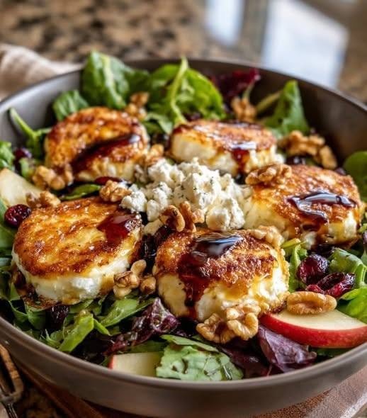 🥗 Warm Goat Cheese Salad with Walnuts Some salads are light and refreshing, while others are so satisfying that they can easily become the main event. This Warm Goat Cheese Salad with Walnuts is one of those recipes. I love making this when I want something that feels a little fancy without actually requiring a lot of work. The first time I served it at home, I wasn't expecting such a simple combination to get so much attention. But once the warm goat cheese came out of the oven, soft and creamy with lightly toasted edges, everyone wanted to dig in. And I completely understood. You get crisp greens, crunchy walnuts, juicy tomatoes, golden toasted baguette, and warm goat cheese that practically melts into every bite. A tangy Dijon vinaigrette pulls everything together, while a little honey adds just enough sweetness to balance the goat cheese. It's the kind of salad I make when I'm craving something fresh but still want that cozy, comforting feeling of a warm meal. ❤️ Why You'll Love This Salad Warm, creamy goat cheese instead of cold crumbles Crunchy walnuts add wonderful texture Toasted baguette makes it surprisingly filling Fresh greens keep everything light Dijon dressing adds a bright, tangy finish A touch of honey balances the tangy cheese Ready in about 30 minutes Beautiful enough for guests but easy enough for a weeknight This recipe is inspired by the classic French salade de chèvre chaud, a bistro favorite built around warm goat cheese, toasted bread, greens, walnuts, and a mustard-based dressing. 🛒 Ingredients You'll Need For the Warm Goat Cheese Toasts 1 goat cheese log, about 8 ounces 4–6 slices crusty baguette 1 tablespoon olive oil 1 tablespoon honey 1 teaspoon fresh thyme leaves Freshly ground black pepper For the Salad 6 cups mixed salad greens 1 cup cherry tomatoes, halved 1/2 cup walnuts, roughly chopped 2 tablespoons fresh parsley or chives, optional For the Dijon Vinaigrette 3 tablespoons extra-virgin olive oil 1 tablespoon balsamic vinegar 1 tablespoon Dijon mustard 1 teaspoon honey 1 small garlic clove, finely minced 1/4 teaspoon salt 1/4 teaspoon freshly ground black pepper Optional 2 slices cooked bacon, crumbled Thinly sliced pear Fresh figs Apple slices Balsamic glaze The combination of goat cheese, walnuts, honey, greens, and Dijon is characteristic of several French-style versions of this salad, while tomatoes, bacon, pears, and figs are easy variations. 👩‍🍳 How to Make Warm Goat Cheese Salad 1. Make the Dressing Start with the vinaigrette. Add the olive oil, balsamic vinegar, Dijon mustard, honey, garlic, salt, and black pepper to a small bowl. Whisk until smooth and emulsified. Taste and adjust if needed. Want it more tangy? Add another splash of vinegar. Want it slightly sweeter? Add a little more honey. Set aside. 2. Toast the Walnuts Place the walnuts in a dry skillet over medium heat. Toast for about 3–5 minutes, stirring frequently. As soon as they smell nutty and fragrant, transfer them to a plate. Don't walk away from them—walnuts can burn quickly. Toasting them makes a noticeable difference. They become crunchier, more aromatic, and much more flavorful. 3. Prepare the Goat Cheese Preheat your oven to 400°F (200°C). Slice the goat cheese log into rounds about 1/2 inch thick. If the cheese is very soft, refrigerate it for 10–15 minutes before slicing. This makes the rounds much easier to handle. Place the baguette slices on a baking sheet. Top each slice with a round of goat cheese. Drizzle each piece with a little honey and sprinkle with fresh thyme and black pepper. Brush the exposed edges of the bread lightly with olive oil. 4. Warm the Goat Cheese Place the tray in the oven and bake for 5–8 minutes. The goat cheese should become soft and creamy, with lightly golden edges. For extra browning, turn on the broiler for the final 30–60 seconds. Watch closely. You want beautifully browned cheese—not burnt cheese! The classic preparation uses a hot grill/broiler to warm the goat cheese until it becomes soft and runny in the center and lightly browned on top. 🥬 5. Dress the Greens Place the salad greens and halved cherry tomatoes in a large bowl. Drizzle with about half of the dressing. Toss gently. Don't add all the dressing at once. It's much easier to add more than to rescue an overdressed salad. 🌰 6. Assemble the Salad Divide the dressed greens between four plates. Scatter the toasted walnuts over each serving. Add fresh parsley or chives if using. Then carefully place one or two warm goat cheese toasts on top. Drizzle with the remaining dressing. For an extra-special finish, add a tiny drizzle of honey or balsamic glaze. Serve immediately. 🧀 Choosing the Best Goat Cheese For this recipe, look for a firm goat cheese log, sometimes called a chèvre log. It should be firm enough to slice into rounds but creamy enough to soften beautifully when heated. A goat cheese log is particularly well suited to this dish because it can be cut into rounds and warmed on toasted baguette. Very soft spreadable goat cheese can still be used, but it may melt much more quickly and won't hold its shape as well. 🌰 Don't Skip the Toasted Walnuts This might seem like a small detail, but toasted walnuts are one of my favorite parts of this salad. The warm goat cheese is creamy and tangy. The greens are fresh. The dressing is bright. The walnuts bring that deep, nutty crunch that makes every bite more interesting. If you have five extra minutes, toast them. You'll be glad you did. 🍐 Delicious Variations Warm Goat Cheese Salad with Pear Add thinly sliced ripe pear to the greens. The sweet, juicy fruit is wonderful with tangy goat cheese and walnuts. Apple & Walnut Version Use crisp apple slices instead of tomatoes for a fresh fall-inspired salad. Fig & Goat Cheese Salad Add fresh figs when they're in season. Their natural sweetness works beautifully with goat cheese. Bacon Goat Cheese Salad Cook a couple of bacon slices until crisp, crumble them, and scatter them over the salad. The salty bacon is fantastic with the sweet honey and tangy cheese. Roasted Beet Version Add roasted beets for an earthy, colorful variation. Extra-Herby Salad Add fresh thyme, chives, parsley, or a little rosemary. 🥖 What Bread Works Best? A crusty baguette is my first choice. You want something sturdy enough to support the warm cheese without falling apart. Good alternatives include: Sourdough Ciabatta Rustic country bread Multigrain bread Slice it fairly thinly so it becomes crisp around the edges while the center remains sturdy. 💡 Tips for the Best Results Keep the greens dry Wash and dry your salad greens thoroughly. Excess water will dilute your vinaigrette. Chill soft goat cheese before slicing Ten to fifteen minutes in the refrigerator can make a huge difference when cutting the cheese. Don't overheat the cheese The goal is soft, creamy goat cheese—not cheese that completely disappears into the bread. Dress the salad lightly The goat cheese, walnuts, and dressing already bring plenty of flavor. Toast the walnuts It takes only a few minutes and makes the salad taste much more special. Add basil or herbs at the end Fresh herbs taste brightest when they're added just before serving. Serve immediately This salad is at its best when the cheese is still warm and creamy. 🥗 What to Serve With Warm Goat Cheese Salad As a starter, this salad is wonderful on its own. For a larger meal, serve it with: Roast chicken Grilled salmon Grilled shrimp Roasted vegetables Vegetable soup Tomato soup French onion soup Grilled steak For lunch, I often add grilled chicken and call it a complete meal. ⏰ Can I Make It Ahead? Yes—but prepare the components separately. You can make the vinaigrette 1–2 days ahead and keep it refrigerated. The walnuts can also be toasted ahead of time and stored in an airtight container. The goat cheese can be sliced several hours ahead and kept refrigerated. When you're ready to eat, warm the cheese, dress the greens, and assemble everything just before serving. That way, the salad stays crisp and the goat cheese stays wonderfully warm. 🧊 How to Store Leftovers The assembled salad is best eaten immediately. If you have leftovers, store the components separately whenever possible. Keep the dressed greens, walnuts, goat cheese toasts, and dressing in separate containers. Refrigerate and use within 2–3 days. For the best texture, rewarm the goat cheese toast in a toaster oven or regular oven rather than microwaving it. ❓ Frequently Asked Questions What is warm goat cheese salad? It's a French-style salad commonly known as salade de chèvre chaud. It traditionally features fresh greens topped with warm goat cheese, often served on toasted bread with walnuts and a mustard-based dressing. Can I use crumbled goat cheese? You can, but I recommend a goat cheese log for this recipe. A log can be sliced into rounds and warmed while maintaining its shape. Can I make it without bread? Absolutely. Warm the goat cheese rounds on a parchment-lined baking sheet and place them directly over the greens. Can I use pecans instead of walnuts? Yes. Pecans make a delicious substitute. Hazelnuts, almonds, and pine nuts also work well. Can I use honey? Definitely. Honey adds a lovely sweet contrast to the tangy goat cheese. You can drizzle it over the cheese before warming or add a little to the vinaigrette. Can I use balsamic vinegar? Yes. Balsamic vinegar is excellent with goat cheese and walnuts. Can I use arugula? Absolutely. Arugula gives the salad a peppery bite that works particularly well with creamy goat cheese. Can I make this salad vegetarian? Yes, as written it is vegetarian. Simply leave out the optional bacon. Why did my goat cheese melt completely? The cheese may have been too soft, or it was heated for too long. Use a firmer goat cheese log and keep the heating time short. Can I add chicken? Yes. Sliced grilled chicken makes this a more substantial lunch or dinner. 📝 Recipe at a Glance Recipe: Warm Goat Cheese Salad with Walnuts Prep Time: 15 minutes Cook Time: 8 minutes Total Time: About 25 minutes Servings: 4 Course: Salad / Lunch / Starter Cuisine: French-inspired Difficulty: Easy ❤️ Final Thoughts There is something wonderfully comforting about this Warm Goat Cheese Salad with Walnuts. Maybe it's the creamy cheese coming straight from the oven. Maybe it's the crunch of toasted walnuts or the warm baguette underneath. Or maybe it's simply the contrast between something fresh and something cozy on the same plate. I love serving this when I want dinner to feel a little more special without making a complicated recipe. It's especially lovely on a relaxed weekend when everyone can sit around the table and take their time. Put the salad in the center, bring out the warm goat cheese toasts, and watch how quickly they disappear. Because once you have that first bite—the crisp greens, tangy melted goat cheese, crunchy walnuts, sweet honey, and sharp Dijon dressing—you realize this isn't just another salad. It's a little French bistro moment at home. 🇫🇷❤️