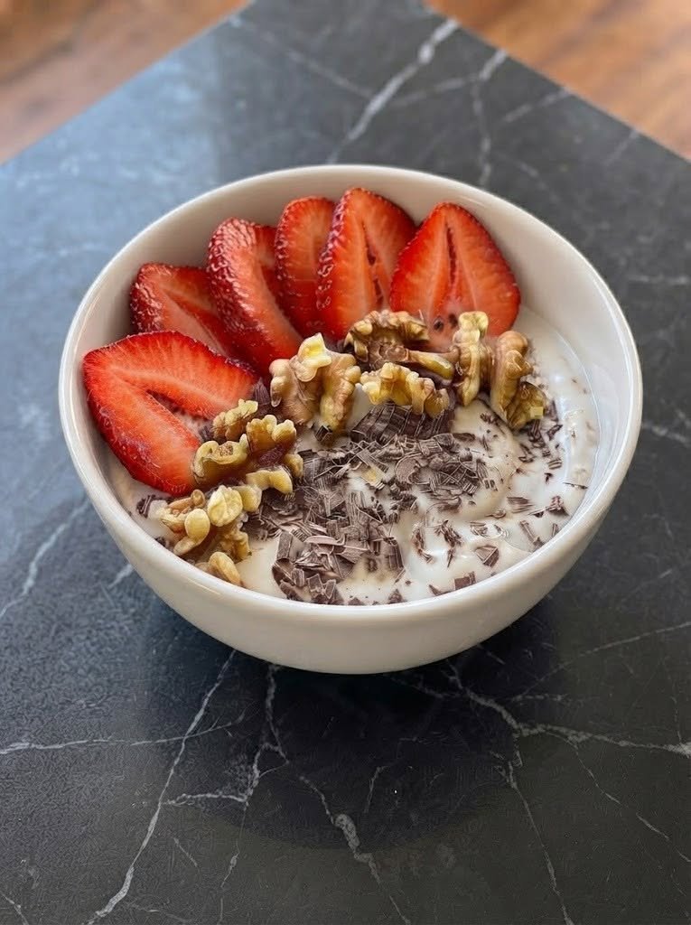 🍓 Keto Yogurt Bowl with Strawberries, Walnuts & Chocolate There are mornings when I want something sweet, creamy, and satisfying—but I definitely don't want to spend 30 minutes in the kitchen. That's exactly how this Keto Yogurt Bowl with Strawberries, Walnuts & Chocolate became one of my favorite quick recipes. I first made it on a weekend when I was craving something that felt a little indulgent. I opened the fridge, grabbed some thick Greek yogurt and strawberries, then added walnuts and a little sugar-free chocolate. What started as a "let's see what happens" breakfast turned into something I ended up making again and again. The combination is just so good. The yogurt is cool and creamy, the strawberries add a fresh burst of sweetness, walnuts bring that buttery crunch, and the little pieces of dark chocolate make every bite feel like a treat. It's one of those recipes that reminds me that keto food doesn't have to be complicated—or boring. ❤️ Why You'll Love This Keto Yogurt Bowl Ready in about 5 minutes No cooking required Creamy, crunchy, fruity, and chocolatey all at once Easy to customize Perfect for breakfast, a snack, or a light dessert Naturally gluten-free Easy to make ahead Uses simple ingredients Low-carb yogurt bowls commonly pair Greek yogurt with small portions of berries, nuts, and sugar-free chocolate for a satisfying combination of creamy and crunchy textures. 🛒 Ingredients You'll Need For the Yogurt Base 1 1/2 cups full-fat plain Greek yogurt 1–2 tablespoons powdered allulose or monk fruit sweetener, to taste 1/2 teaspoon vanilla extract Pinch of salt For the Toppings 1/2 cup fresh strawberries, sliced 1/4 cup walnuts, roughly chopped 2 tablespoons sugar-free dark chocolate chips or chopped sugar-free dark chocolate 1 teaspoon unsweetened cocoa powder, optional Optional Extras 1 tablespoon unsweetened shredded coconut 1 tablespoon chia seeds 1 tablespoon unsweetened almond butter A few raspberries Sugar-free chocolate drizzle Pinch of cinnamon Tip: If you're following keto strictly, choose yogurt and chocolate with no added sugar and check the nutrition labels because carbohydrate amounts vary considerably between brands. 🥣 How to Make a Keto Yogurt Bowl 1. Make the Creamy Yogurt Base Add the Greek yogurt to a bowl. Stir in the vanilla, powdered sweetener, and a tiny pinch of salt. Mix until smooth and creamy. Give it a taste before adding the toppings. If you prefer a sweeter bowl, add a little more sweetener. I actually like keeping the yogurt only lightly sweetened because the strawberries and chocolate provide plenty of flavor. 2. Prepare the Strawberries Wash and dry the strawberries thoroughly. Remove the stems and slice them. For an especially pretty bowl, slice some strawberries thinly and leave a few pieces slightly larger. If your strawberries aren't particularly sweet, toss them with a tiny pinch of your preferred keto sweetener and let them sit for 2–3 minutes. 3. Toast the Walnuts This step is optional, but it's one of my favorite little upgrades. Place the chopped walnuts in a dry skillet over medium-low heat. Toast for about 3–4 minutes, stirring frequently. As soon as they smell nutty and fragrant, remove them from the pan. Let them cool for a minute before adding them to the bowl. Toasting gives the walnuts a warmer, richer flavor and makes their crunch even better. 4. Assemble the Bowl Spoon the sweetened Greek yogurt into a serving bowl. Arrange the strawberries over one side. Add the toasted walnuts. Scatter the sugar-free chocolate chips or chopped chocolate over the top. If you're using cocoa powder, lightly dust it over everything. For an extra pretty presentation, finish with a tiny drizzle of sugar-free chocolate or almond butter. That's it! No blender. No oven. No complicated preparation. Just stir, top, and eat. 🍫 The Chocolate Makes It Special You don't need a huge amount of chocolate here. A couple of tablespoons of chopped sugar-free dark chocolate are enough to give you those little rich, chocolatey bites throughout the bowl. I prefer chopped dark chocolate because you get different-sized pieces—some tiny flecks and some bigger chunks. Sugar-free chocolate chips are also convenient and work beautifully. If you prefer a stronger chocolate flavor, mix 1 teaspoon unsweetened cocoa powder directly into the yogurt. You can even make the base chocolatey and then add chocolate chips on top. Yes, I've done that. And yes, it's delicious. 🍓 Choosing Strawberries for Keto Strawberries are one of my favorite fruits to use in low-carb recipes because you can add a modest portion without needing a lot of fruit to make the bowl feel fresh and colorful. For this recipe, about 1/2 cup sliced strawberries is enough for two servings. If you want to keep the bowl lower in carbohydrates, you can reduce the strawberry portion slightly and add a few raspberries instead. Always account for the specific quantities and nutrition information of the ingredients you're using. 🌰 Don't Skip the Walnuts The walnuts aren't just there for decoration. Without them, the bowl is mostly soft textures. The walnuts give you that satisfying crunch that makes each spoonful more interesting. They also pair beautifully with chocolate. If walnuts aren't your favorite, try: Pecans Almonds Macadamia nuts Hazelnuts Pumpkin seeds For a nut-free version, use sunflower seeds or pumpkin seeds. ✨ Easy Variations Chocolate Strawberry Cheesecake Bowl Add 1 tablespoon softened cream cheese to the yogurt and stir until completely smooth. The result is thicker, richer, and reminiscent of cheesecake. Peanut Butter Chocolate Bowl Add 1 tablespoon natural peanut butter or unsweetened almond butter. Top with strawberries and sugar-free chocolate. It's basically a peanut-butter-and-jelly-inspired dessert bowl without the bread. Cinnamon Strawberry Bowl Add 1/4 teaspoon cinnamon to the yogurt. The cinnamon gives the strawberries a warmer, sweeter flavor. Raspberry Chocolate Bowl Replace half or all of the strawberries with raspberries. Raspberries bring a lovely tartness that works especially well with dark chocolate. Coconut Chocolate Bowl Add 1 tablespoon unsweetened shredded coconut and swap the walnuts for chopped macadamias. This one tastes almost like a keto-friendly chocolate-coconut dessert. High-Protein Version Stir an unsweetened or keto-friendly vanilla protein powder into the yogurt. You may need a splash of unsweetened almond milk to loosen the mixture. 🥄 How to Make It Extra Thick If you love those really thick, spoon-standing yogurt bowls, start with strained full-fat Greek yogurt. You can also place the yogurt in the refrigerator for a little while before assembling the bowl. For an even thicker dessert-like texture, stir in: 1 tablespoon chia seeds, or 1 tablespoon ground flaxseed Then let the mixture sit for about 10 minutes. The texture will become noticeably thicker. 🍯 Can I Use Regular Honey? If you're following a strict keto diet, regular honey isn't the best choice because it adds a significant amount of sugar. Instead, use: Allulose Monk fruit Stevia Erythritol Choose the sweetener you personally prefer and adjust it according to its sweetness. ☕ When I Like to Make This Bowl This recipe is especially handy when I want something quick. For Breakfast Pair it with coffee or tea for an easy start to the morning. For an Afternoon Snack It's a great way to satisfy a sweet craving without turning the kitchen upside down. For Dessert Make smaller portions and add extra dark chocolate. Honestly, this is probably my favorite way to serve it. For a Weekend Brunch Set out bowls of yogurt, strawberries, walnuts, chocolate, coconut, and other keto-friendly toppings and let everyone build their own. It's simple and feels surprisingly special. ⏰ Can You Make It Ahead? Yes, but I recommend keeping the toppings separate. You can mix the yogurt base and refrigerate it for up to 2 days. Store the strawberries separately so they don't release too much liquid into the yogurt. Keep the walnuts and chocolate in separate containers at room temperature. When you're ready to eat, assemble everything fresh. This keeps the walnuts crunchy and the strawberries bright. 🧊 Storage Once assembled, the yogurt bowl is best eaten immediately or within a few hours. If you have leftovers, cover and refrigerate them. The yogurt itself can keep for several days, but strawberries will gradually release moisture and soften the nuts. For the best texture, store the components separately whenever possible. ❓ Frequently Asked Questions Is Greek yogurt keto? Plain Greek yogurt can fit into a keto diet, but the carbohydrate content varies by brand and serving size. Choose unsweetened yogurt and check the nutrition label. Can I use regular yogurt? Yes, but Greek yogurt is thicker and generally gives the bowl a richer texture. Can I use low-fat Greek yogurt? Absolutely. Full-fat yogurt gives the bowl a creamier, more satisfying texture, but low-fat Greek yogurt can also work. What chocolate is best for keto? Look for unsweetened or sugar-free dark chocolate with minimal added sugar. Check the nutrition label because sugar-free products can vary in carbohydrate content. Can I use frozen strawberries? Yes, but fresh strawberries are better for this particular bowl. If using frozen berries, thaw them completely and drain excess liquid before adding them. Can I use raspberries instead? Definitely. Raspberries make an excellent low-carb alternative to strawberries. Can I add chia seeds? Yes. Chia seeds add texture and help make the yogurt thicker. How can I make the bowl sweeter without adding sugar? Use powdered allulose, monk fruit, stevia, or another keto-friendly sweetener. Can I make this dairy-free? Yes. Replace the Greek yogurt with an unsweetened dairy-free keto yogurt made from coconut, almond, or another suitable base. 📝 Recipe at a Glance Prep Time: 5 minutes Cook Time: 0 minutes Total Time: 5 minutes Servings: 2 Category: Breakfast, Snack, Dessert Cuisine: American-inspired Method: No-cook 🍓 Keto Yogurt Bowl with Strawberries, Walnuts & Chocolate Ingredients 1 1/2 cups full-fat plain Greek yogurt 1–2 tablespoons powdered allulose or monk fruit sweetener 1/2 teaspoon vanilla extract Pinch of salt 1/2 cup sliced strawberries 1/4 cup chopped walnuts 2 tablespoons sugar-free dark chocolate chips or chopped dark chocolate 1 teaspoon unsweetened cocoa powder, optional Instructions Add Greek yogurt to a bowl. Stir in vanilla, sweetener, and salt until smooth. Slice the strawberries. Toast walnuts in a dry skillet for 3–4 minutes, if desired. Divide yogurt between two bowls. Top with strawberries, walnuts, and sugar-free chocolate. Dust with cocoa powder if using. Add any optional toppings. Serve immediately. ❤️ Final Thoughts Sometimes the recipes I make most often are the ones that take almost no effort. This Keto Yogurt Bowl with Strawberries, Walnuts & Chocolate is exactly that kind of recipe. It's creamy without being heavy, sweet without needing regular sugar, crunchy from the walnuts, and chocolatey enough to make you feel like you're having dessert for breakfast. And I love that you can change it depending on your mood. Some days it's strawberries and chocolate. Other days it's raspberries, pecans, and cinnamon. And when I'm really craving dessert, I add a little extra sugar-free chocolate and call it dessert. Five minutes, a handful of ingredients, and a bowl full of something genuinely delicious—that's a recipe worth keeping around.