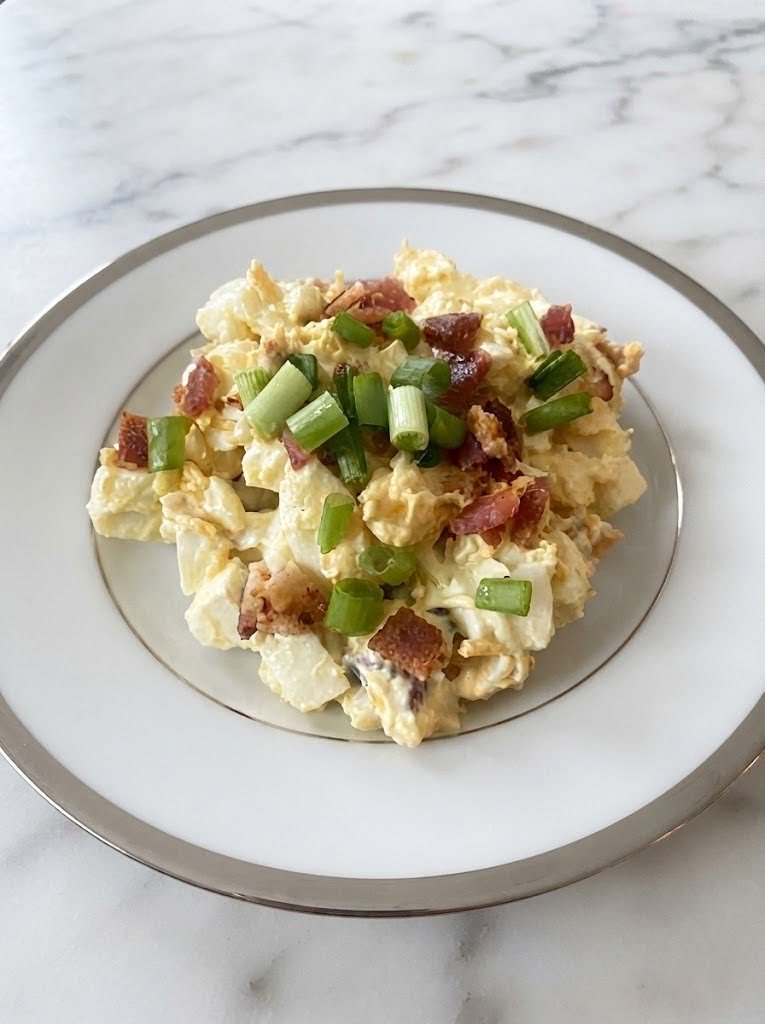 🥓 Keto Bacon Ranch Egg Salad There are some recipes that are so easy you almost don't expect them to be exciting—but then you take the first bite and wonder why you didn't make them sooner. This Keto Bacon Ranch Egg Salad is exactly that kind of recipe. Creamy chopped eggs, crispy bacon, tangy ranch seasoning, sharp cheddar, and fresh green onions come together in a bowl that tastes like a cross between classic egg salad and a loaded ranch dip. It's rich, savory, crunchy, and incredibly satisfying. I love making this when I need an easy lunch that doesn't require much thought. It's also one of those recipes that works beautifully for meal prep because it can be made ahead and kept chilled in the refrigerator. Keto egg salads commonly use mayonnaise and hard-boiled eggs as their creamy base, while bacon and ranch bring extra savory flavor. The first time I made this for a weekend lunch, I thought I'd have leftovers for the next day. That plan didn't last long. Someone kept sneaking spoonfuls straight from the bowl, and by dinner there was barely enough left for one serving. And honestly, I wasn't even disappointed. ❤️ Why You'll Love This Keto Egg Salad Creamy and incredibly flavorful Crispy bacon in every bite Classic ranch flavor Naturally low-carb High in protein and satisfying Takes only about 15 minutes once the eggs are cooked Perfect for meal prep No bread required Easy to customize Delicious cold straight from the refrigerator You can serve it in lettuce cups, over greens, inside a low-carb wrap, or simply eat it with a fork. 🛒 Ingredients For the Egg Salad 6 large hard-boiled eggs, peeled 5 slices bacon, cooked until crisp 1/2 cup mayonnaise 1 1/2 tbsp ranch seasoning 1/3 cup shredded sharp cheddar cheese 2 tbsp finely sliced green onions 1 tbsp finely chopped fresh parsley 1 tsp Dijon mustard 1/4 tsp garlic powder 1/4 tsp black pepper Salt, to taste Optional Add-Ins 1/3 cup finely diced celery 1 tbsp chopped fresh dill 1–2 tbsp finely chopped dill pickles 1/4 tsp smoked paprika A pinch of cayenne pepper Extra cheddar Extra crispy bacon 🥚 How to Make Keto Bacon Ranch Egg Salad Step 1: Cook the Bacon Start with the bacon because you want it nice and crisp. Cook the bacon in a skillet over medium heat until browned and crisp. Transfer it to a paper towel-lined plate and allow it to cool. Once cool enough to handle, chop or crumble it into small pieces. Don't make the pieces too tiny. I like having a few bigger crispy bits throughout the salad. 🥚 Step 2: Prepare the Eggs If you don't already have hard-boiled eggs prepared, cook six eggs until the yolks are fully set. Cool them completely in cold water, peel them, and pat them dry. Chop the eggs into bite-sized pieces. I prefer a mixture of larger chunks and slightly mashed pieces. That gives the salad a creamy texture while still leaving you with recognizable pieces of egg. A classic keto egg salad also works well with chopped hard-boiled eggs mixed into mayonnaise and seasonings. 🥣 Step 3: Make the Ranch Dressing Mixture In a large mixing bowl, combine: Mayonnaise Ranch seasoning Dijon mustard Garlic powder Black pepper Stir until smooth. Taste before adding salt. Ranch seasoning and bacon can both be salty, so you may not need much—or any—additional salt. 🧀 Step 4: Add Everything Together Add the chopped eggs to the bowl. Then add: Crispy bacon Cheddar cheese Green onions Fresh parsley Gently fold everything together. Don't stir too aggressively. You want the eggs to stay chunky rather than turning into a completely smooth paste. If the salad looks a little dry, add another tablespoon of mayonnaise. ❄️ Step 5: Chill Cover the bowl and refrigerate for at least 30 minutes. If you have time, let it chill for 1–2 hours. That little resting period gives the ranch seasoning time to blend into the creamy dressing and lets the flavors come together. Bacon-ranch egg salad is also well suited to make-ahead lunches; similar recipes recommend chilling before serving and keeping the salad refrigerated. 🥬 How to Serve Keto Bacon Ranch Egg Salad This is where you can have some fun. Lettuce Cups Spoon the egg salad into crisp butter lettuce or romaine leaves. It's fresh, crunchy, and easy to eat. Low-Carb Wrap Spread the egg salad into a keto tortilla and add lettuce and sliced tomato if desired. Avocado Boats Scoop the salad into halved avocados. The creamy avocado and ranch egg salad combination is seriously good. Cucumber Rounds Spoon small portions onto thick cucumber slices for an easy party appetizer. Over a Salad Serve a scoop over mixed greens with extra bacon, cheddar, and ranch dressing. Straight From the Bowl No judgment. Sometimes the fork is the best serving utensil. 🥓 Make It Extra Loaded If you're making this for a weekend lunch or casual gathering, turn it into a loaded bacon ranch egg salad. Add: Extra crispy bacon More cheddar Chopped green onions Diced avocado Fresh dill A sprinkle of smoked paprika You can even top each serving with a little extra ranch seasoning and freshly cracked black pepper. ✨ Tips for the Best Egg Salad Don't overcook the eggs Overcooked eggs can develop dry, chalky yolks. You want the yolks fully set but still creamy. Let the bacon get really crisp Soft bacon disappears into the creamy egg mixture. Crispy bacon gives you those delicious little salty bites. Chill before serving The flavors improve after the salad has had a little time to rest. Don't over-mash the eggs Some chunky pieces make the texture much more interesting. Taste before salting Bacon, ranch seasoning, cheddar, and mayonnaise can all contribute salt. Use sharp cheddar A little sharp cheddar gives the salad much more flavor than mild cheese. 🌿 Easy Variations Spicy Bacon Ranch Egg Salad Add 1/4 teaspoon cayenne pepper and a few dashes of hot sauce. For even more heat, add finely chopped jalapeño. Dill Pickle Bacon Ranch Add 1–2 tablespoons finely chopped dill pickles plus a teaspoon of pickle juice. The tanginess is fantastic with the rich dressing. Avocado Bacon Ranch Fold in one diced avocado right before serving. Because avocado browns, this version is best eaten the same day. Bacon Cheddar Ranch Double the cheddar and add extra bacon. This one is especially good stuffed into lettuce wraps. Ranch & Dill Add fresh dill and parsley for an extra-herby flavor. 🥗 What to Serve With It For a complete keto lunch, serve the egg salad with: Avocado Cucumber salad Roasted broccoli Cauliflower bites Mixed greens Celery sticks Cucumber slices Olives Pickles Cheese crisps For a party, put the egg salad in a serving bowl surrounded by cucumber slices, celery, bell pepper strips, and low-carb crackers. ⏰ Can I Make This Ahead? Absolutely. This is one of the reasons I love egg salad for busy weeks. Prepare the entire recipe, cover it tightly, and refrigerate it. The flavors actually become more blended after chilling. If you're meal-prepping it, divide it into individual containers so you can grab one for lunch. Keep it refrigerated rather than leaving it sitting at room temperature for extended periods. Similar prepared egg salads are intended to be stored chilled. 🧊 How Long Does Keto Bacon Ranch Egg Salad Last? Store the egg salad in an airtight container in the refrigerator and enjoy it within 3–4 days. If you've added avocado, the texture and color are best when eaten sooner. Don't freeze egg salad—the mayonnaise and eggs can develop an unpleasant texture after thawing. ❓ Frequently Asked Questions Is bacon ranch egg salad keto? Yes, this version is designed to be keto-friendly, using eggs, bacon, mayonnaise, cheese, and ranch seasoning without bread, sugar, or high-carb fillers. Always check your specific ranch seasoning and mayonnaise labels because formulations vary. How many eggs should I use? Six large eggs make about four generous servings. For a larger gathering, simply double the recipe. Can I use turkey bacon? Yes. Turkey bacon works, although regular bacon generally gives you a richer flavor and crispier texture. Can I use ranch dressing instead of ranch seasoning? Yes, but you'll need to adjust the mayonnaise because bottled ranch dressing is thinner. Start by replacing part of the mayonnaise with ranch dressing and add more only if needed. Can I use Greek yogurt instead of mayonnaise? You can substitute part of the mayonnaise with full-fat Greek yogurt. The result will be tangier and slightly lighter. What cheese is best? Sharp cheddar is my favorite, but Monterey Jack, Colby Jack, pepper Jack, or even crumbled blue cheese can work. Can I make it without cheese? Absolutely. The cheese is optional. The bacon and ranch already provide plenty of flavor. Can I add pickles? Definitely. Finely chopped dill pickles are one of my favorite additions because their acidity cuts through the richness. How do I keep the salad from getting watery? Make sure your eggs are completely cooled and dry before chopping. If you're adding pickles or celery, drain them well before mixing. 📝 Recipe at a Glance Prep Time: 10 minutes Cook Time: 10–12 minutes for eggs and bacon Chill Time: 30 minutes Total Time: About 40–45 minutes Servings: 4 Course: Lunch / Salad / Snack Cuisine: American-inspired Diet: Keto / Low-Carb 🥓 Keto Bacon Ranch Egg Salad Recipe Ingredients 6 large hard-boiled eggs, peeled 5 slices bacon, cooked and crumbled 1/2 cup mayonnaise 1 1/2 tbsp ranch seasoning 1/3 cup shredded sharp cheddar 2 tbsp green onions 1 tbsp fresh parsley 1 tsp Dijon mustard 1/4 tsp garlic powder 1/4 tsp black pepper Salt, to taste Instructions Cook bacon until crisp. Drain and crumble. Chop cooled hard-boiled eggs into bite-sized pieces. In a bowl, mix mayonnaise, ranch seasoning, Dijon, garlic powder, and pepper. Fold in chopped eggs, bacon, cheddar, green onions, and parsley. Taste and add salt if needed. Cover and refrigerate for at least 30 minutes. Serve in lettuce cups, avocado halves, low-carb wraps, over greens, or straight from the bowl. ❤️ Final Thoughts This Keto Bacon Ranch Egg Salad is the kind of recipe that earns a permanent spot in the refrigerator. It's creamy without being boring, loaded with crispy bacon, packed with ranch flavor, and just cheesy enough to make every bite feel indulgent. I especially love it on those days when I don't want to cook a complicated lunch. A little prep, a little chopping, and suddenly there's a satisfying keto-friendly meal waiting in the fridge. And if you're making it for family, I'd recommend hiding one serving for yourself. Because once everyone tastes the bacon-and-ranch combination, that bowl tends to disappear surprisingly quickly. 🥓🥚💚