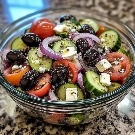 CLASSIC GREEK SALAD Some recipes don't need much explaining. They just need good ingredients. This Classic Greek Salad is one of those recipes. Whenever I make it, I'm reminded of how much I love food that feels fresh, colorful, and completely uncomplicated. There's no long list of ingredients, no complicated dressing to whisk together, and definitely no need to spend an hour in the kitchen. Just ripe tomatoes, crisp cucumber, crunchy onion, sweet green pepper, salty Kalamata olives, creamy feta, oregano, and a generous drizzle of olive oil. That's it. And somehow, those simple ingredients create a salad that tastes like summer in every bite. I especially love making this on weekends when the weather is warm and everyone wants something fresh alongside grilled chicken, fish, or simply some warm bread. It has become one of those recipes I can throw together almost without thinking. The first time I served it to my family, I expected it to be more of a side dish. Instead, everyone kept going back for another helping. Someone scooped up the tomatoes. Someone grabbed more feta. And, of course, someone discovered that the best part was the flavorful olive oil and tomato juices collecting at the bottom of the bowl. That's when I knew this salad was going to become a regular. Traditional Greek salad, known as horiatiki, is a rustic village-style salad built around tomatoes, cucumber, onion, peppers, olives, feta, oregano, and olive oil. Unlike many international versions, it traditionally contains no lettuce. And honestly? I think that's part of its charm. There is nowhere for mediocre ingredients to hide. When the vegetables are good, the salad is spectacular. ❤️ Why You'll Love This Classic Greek Salad Fresh, crunchy, and colorful Ready in about 15 minutes No cooking required No complicated dressing Naturally vegetarian Perfect for summer lunches and dinners Wonderful alongside grilled meats and seafood Great for Mediterranean-style meals Naturally gluten-free when served without bread Easy to customize Absolutely delicious with warm pita or crusty bread The beauty of horiatiki is its simplicity. The vegetables are usually cut into generous pieces rather than finely chopped, and the feta is traditionally served prominently on top rather than disappearing into the salad. 🛒 Ingredients For the Salad 4 medium ripe tomatoes 1 large cucumber 1 small red onion 1 green bell pepper ¾ cup Kalamata olives 6–8 oz Greek feta cheese ¼ cup extra-virgin olive oil 1 teaspoon dried Greek oregano ½ teaspoon sea salt ¼ teaspoon freshly ground black pepper Optional 1 tablespoon red wine vinegar Freshly squeezed lemon juice A few capers Fresh oregano for garnish Warm pita or crusty bread for serving The traditional ingredient list varies somewhat by region and household. Some versions include red-wine vinegar or lemon, while others rely almost entirely on olive oil, tomato juices, and oregano. 🍅 How to Make Classic Greek Salad 1. Start With the Tomatoes This is the most important part. Choose tomatoes that are ripe, fragrant, and juicy. Cut them into thick wedges or large chunks. Don't finely dice them. You want substantial pieces that stay juicy and give the salad plenty of texture. Place the tomatoes in a wide serving bowl. Sprinkle lightly with salt. Let them sit for about 5–10 minutes. This gives the tomatoes a chance to release some of their juices. And those juices are going to become part of your dressing. 🥒 2. Prepare the Cucumber Wash the cucumber and cut it into thick half-moons. If the skin is particularly tough, peel it partially in stripes. You can also leave the skin completely intact if you prefer. Add the cucumber to the tomatoes. The contrast between juicy tomatoes and cool, crisp cucumber is one of my favorite things about this salad. 🧅 3. Add the Red Onion Thinly slice the red onion. If you find raw onion too strong, place the slices in a bowl of cold water for about 5 minutes, then drain well. This takes away some of the sharp bite while keeping the onion crisp. Scatter the onion over the tomatoes and cucumber. 🫑 4. Add the Green Pepper Remove the seeds and white ribs from the green bell pepper. Cut it into thin rings or strips. Add it to the bowl. The green pepper adds a wonderful crunch and a slightly grassy flavor that balances the sweetness of the tomatoes. 🫒 5. Add the Kalamata Olives Add the Kalamata olives. I prefer whole or roughly halved olives because they feel more rustic and substantial. If you're serving the salad to children or anyone who prefers them pitted, definitely use pitted olives. Traditional versions often use Kalamata olives, although regional variations can include other olives as well. 🧀 6. Add the Feta And now comes one of my favorite parts. Instead of scattering tiny pieces of feta throughout the salad, place a generous block or thick slices right on top. Sprinkle the feta with dried oregano. Then drizzle some of the olive oil directly over it. The creamy feta absorbs a little of the oil and oregano while remaining substantial enough to break apart with your fork as you eat. It's simple, rustic, and beautiful. 🫒 7. Dress the Salad Drizzle the extra-virgin olive oil generously over the vegetables and feta. Add a little more dried oregano. Season with freshly ground black pepper. If you're using red wine vinegar, add a small splash. You don't need a separate dressing. That's one of the things I love about Greek salad. The tomato juices, olive oil, oregano, and feta naturally come together right in the bowl. 🥗 8. Toss Gently Give the vegetables a very gentle toss. Don't aggressively stir the salad. You don't want to crush the tomatoes or break the feta into tiny pieces. I like to toss the vegetables underneath the feta and then leave the feta sitting proudly on top. That way, every person gets a little bit of everything. 🌿 9. Finish and Serve Add another small sprinkle of oregano. Taste and adjust the salt if necessary. Remember that both feta and Kalamata olives can be quite salty, so go easy. Serve immediately or within a short time. And if you're serving bread alongside it, don't throw away the juices at the bottom of the bowl. That's the part you'll want to mop up. ⭐ My Best Tips for the Best Greek Salad Use Room-Temperature Tomatoes This makes a bigger difference than you might expect. Cold tomatoes often don't have the same aroma or sweetness as ripe tomatoes served closer to room temperature. Buy the Best Olive Oil You Can There isn't a complicated dressing here to hide behind. The olive oil is one of the main flavors. Use an extra-virgin olive oil that you genuinely enjoy eating. Don't Chop Everything Too Small Greek salad is rustic. Large, generous pieces give you better texture and make every ingredient easier to taste. Don't Overdress It You want the vegetables coated with olive oil—not swimming in dressing. Don't Over-Salt Feta and olives already bring plenty of saltiness. Season lightly first, then taste. Use Real Feta A good block of feta in brine has a creamy, tangy flavor that's hard to replace. Don't Make It Hours Ahead The longer the tomatoes sit, the more liquid they release. For the freshest texture, assemble it relatively close to serving time. 🧀 Should I Crumble the Feta? You can, but I prefer keeping it in larger pieces. Traditional horiatiki commonly features a substantial slab or thick pieces of feta on top rather than having the cheese completely mixed throughout the vegetables. That said, this is your salad. If you prefer crumbled feta in every bite, go for it. Nobody at my table is going to complain. 🥬 Does Classic Greek Salad Have Lettuce? Traditionally, no. This is one of the biggest differences between traditional horiatiki and many restaurant-style Greek salads outside Greece. Traditional versions are built around chunky vegetables, olives, feta, oregano, and olive oil rather than a base of lettuce. You can certainly add lettuce if you like. It just turns it into your own variation rather than the classic village-style salad. 🍋 Should I Add Lemon Juice? You can. A small squeeze of lemon gives the salad a bright, fresh finish. However, you don't need it. Tomato juice and olive oil already create a delicious natural dressing. Some traditional versions use no acid at all, while others use lemon or red-wine vinegar. 🫒 Can I Use Different Olives? Absolutely. Kalamata olives are the classic choice, but you can use another good Greek olive if that's what you have. Green olives can also be delicious if you prefer a milder, more buttery flavor. 🌶️ Easy Variations Greek Salad With Capers Add a tablespoon of drained capers for extra briny flavor. Capers and caper leaves are used in some Greek island variations. Greek Salad With Avocado Add diced avocado just before serving. This isn't traditional, but it makes the salad extra creamy and filling. Greek Salad With Chickpeas Add a cup of drained chickpeas for a heartier vegetarian lunch. Greek Chicken Salad Top the salad with sliced grilled chicken. It's an easy way to turn a side dish into a complete meal. Greek Salad With Grilled Shrimp Add grilled shrimp seasoned with garlic, oregano, lemon, salt, and pepper. The combination is fantastic. Creamy Greek Salad If you want a more modern restaurant-style version, serve the salad with a little tzatziki on the side. 🍗 What to Serve With Greek Salad This salad goes with almost everything. Try serving it alongside: Grilled chicken Chicken souvlaki Grilled pork chops Lamb kebabs Grilled shrimp Baked fish Roasted chicken Grilled steak Falafel Hummus Tzatziki Warm pita Crusty bread It also makes a beautiful addition to a Mediterranean dinner spread. Put the salad in the center of the table with grilled meat, warm bread, olives, dips, and roasted vegetables. That's the kind of dinner where nobody feels rushed. 🥖 Don't Forget the Bread If you're serving traditional Greek salad, warm bread or pita is one of my favorite additions. Not because the salad needs it. Because there's always that wonderful mixture of olive oil and tomato juices left at the bottom of the bowl. And letting that go to waste feels almost criminal. Take a piece of warm bread. Dip. Take a bite. Repeat. 🧊 How to Store Greek Salad Greek salad is best fresh, but leftovers can be refrigerated in an airtight container for about 1 day for the best texture. The tomatoes and cucumber will release more liquid as they sit. If you know you'll have leftovers, consider keeping the vegetables and dressing separate until you're ready to eat. 🥗 Can I Make Greek Salad Ahead? Yes, with a little planning. You can wash and cut the vegetables several hours ahead and refrigerate them separately. Keep the feta and olives ready to go. Then assemble everything shortly before serving. This gives you the convenience of advance preparation without sacrificing the crisp texture of the vegetables. ❓ Frequently Asked Questions What is a traditional Greek salad called? It's commonly called horiatiki, which means “village” or “country-style” salad. Does authentic Greek salad contain lettuce? Traditional horiatiki does not contain lettuce. It focuses on tomatoes, cucumber, onion, green pepper, olives, feta, oregano, and olive oil. Can I use cherry tomatoes? Absolutely. They aren't the classic choice, but they work very well when they're ripe and sweet. Halve larger cherry tomatoes or leave small ones whole. Can I use English cucumber? Yes. It works beautifully, especially when you want a crisp cucumber with a thinner skin. Can I use crumbled feta? Yes. A block of feta is more traditional, but crumbled feta is perfectly delicious. Can I leave out the green pepper? Of course. The salad will still be delicious. Can I add lettuce? Yes, if you like. It will make the salad more similar to the Greek salads commonly served internationally, though traditional horiatiki doesn't use lettuce. Can I add chicken? Definitely. Grilled chicken turns this into a satisfying complete meal. Is Greek salad keto-friendly? It can fit into a keto-style diet because its core ingredients are relatively low in carbohydrates, but tomatoes, onions, and other vegetables still contribute carbohydrates. Portion size and individual ingredient choices matter. Is Greek salad healthy? It's made primarily from vegetables, olives, feta, and extra-virgin olive oil, making it a nutrient-dense and flavorful salad option. As with any recipe, overall nutrition depends on portions and ingredients. How long does Greek salad last? It's best enjoyed fresh. Once dressed, the vegetables gradually become softer and release more liquid, so leftovers are best eaten within about a day. 🍽️ Recipe at a Glance Prep Time: 15 minutes Cook Time: None Total Time: 15 minutes Servings: 4 Category: Salad / Side Dish Cuisine: Greek / Mediterranean Method: No-cook Difficulty: Easy ❤️ The Salad I Never Get Tired Of Some recipes come and go. This isn't one of them. Classic Greek Salad is the kind of recipe I can make over and over again because it never feels boring. Maybe it's the juicy tomatoes. Maybe it's the crisp cucumber. Maybe it's that salty feta and those briny Kalamata olives. Or maybe it's simply the way good olive oil ties everything together. I love putting a big bowl of this on the table when family is around. It feels generous without being complicated, and somehow everyone finds something they love in it. On a warm weekend, I'll serve it alongside grilled chicken or fish. On a busy afternoon, I'll pile it into a bowl with some warm pita and call it lunch. And when I'm making a bigger Mediterranean-style dinner, this is almost always the salad I reach for. It doesn't need fancy tricks. It doesn't need an elaborate dressing. It just needs good tomatoes, good feta, good olive oil, and a little time to enjoy it. And honestly, isn't that what good food is supposed to be? Simple ingredients. Big flavor. A table full of people going back for another bite.